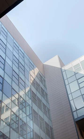 Hero Image Blick hoch zum modernen berlinovo-Büroturm in der Linkstraße, in
großen Glasflächen spiegelt sich die Sonne.