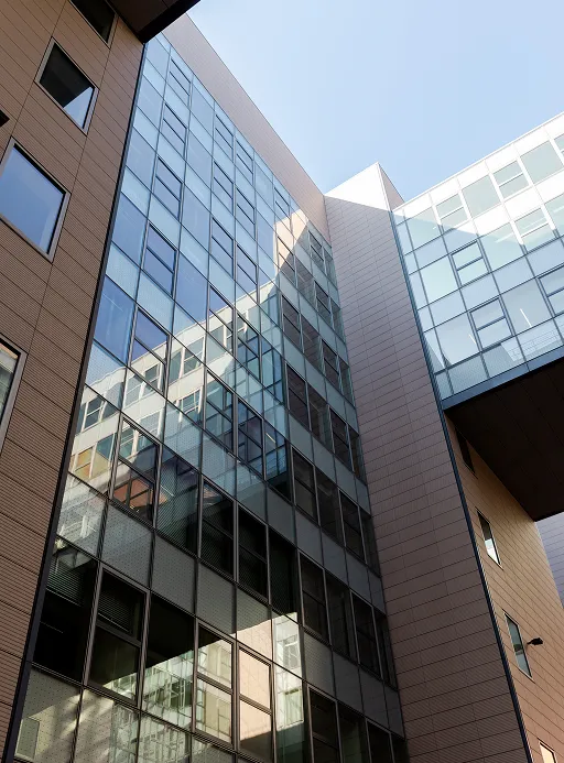 Blick hoch zu dem modernen berlinovo-Büroturm in der Linkstraße, in großen
Glasflächen spiegelt sich die Sonne.